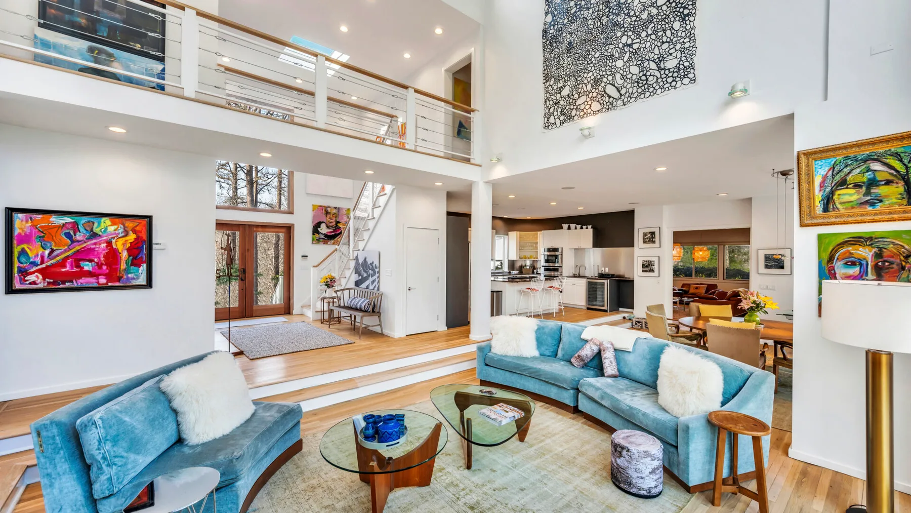 A bright open-plan living room with blue seating and a kitchen in the background.