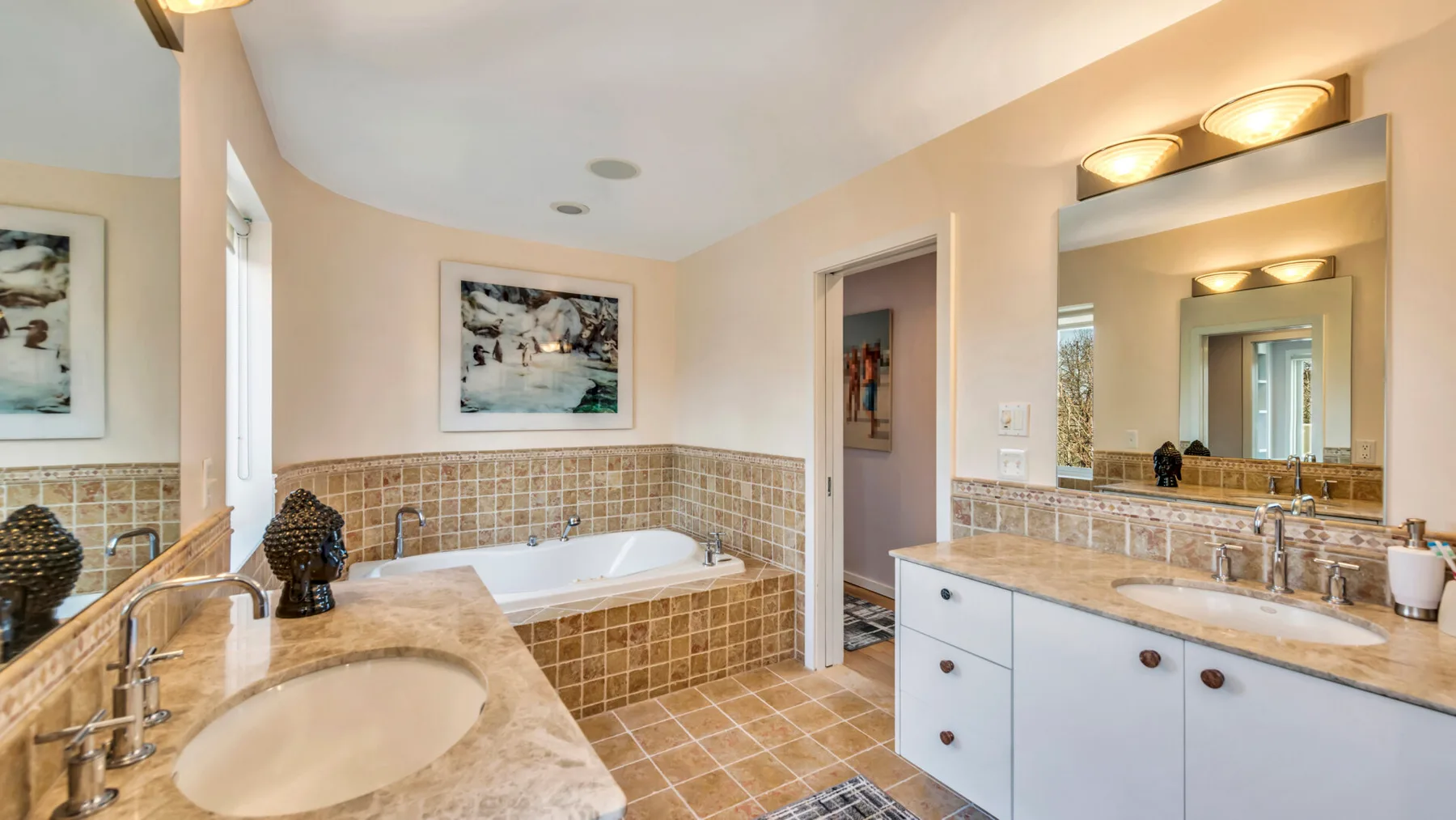 A bathroom with a built-in bathtub and a long vanity with sinks.