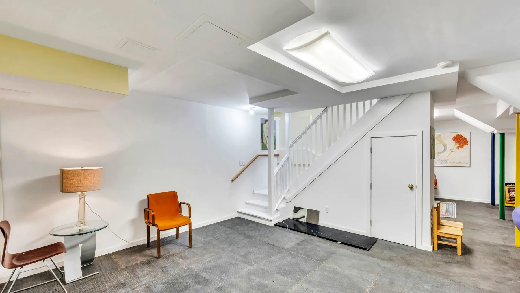 A bright interior room with a staircase and a few chairs.