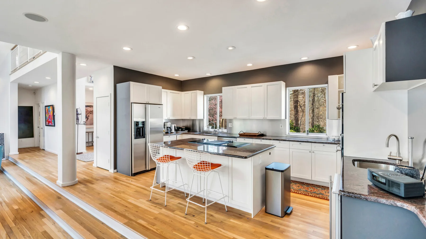 A bright kitchen with a central island, white cabinets, and hardwood flooring.
