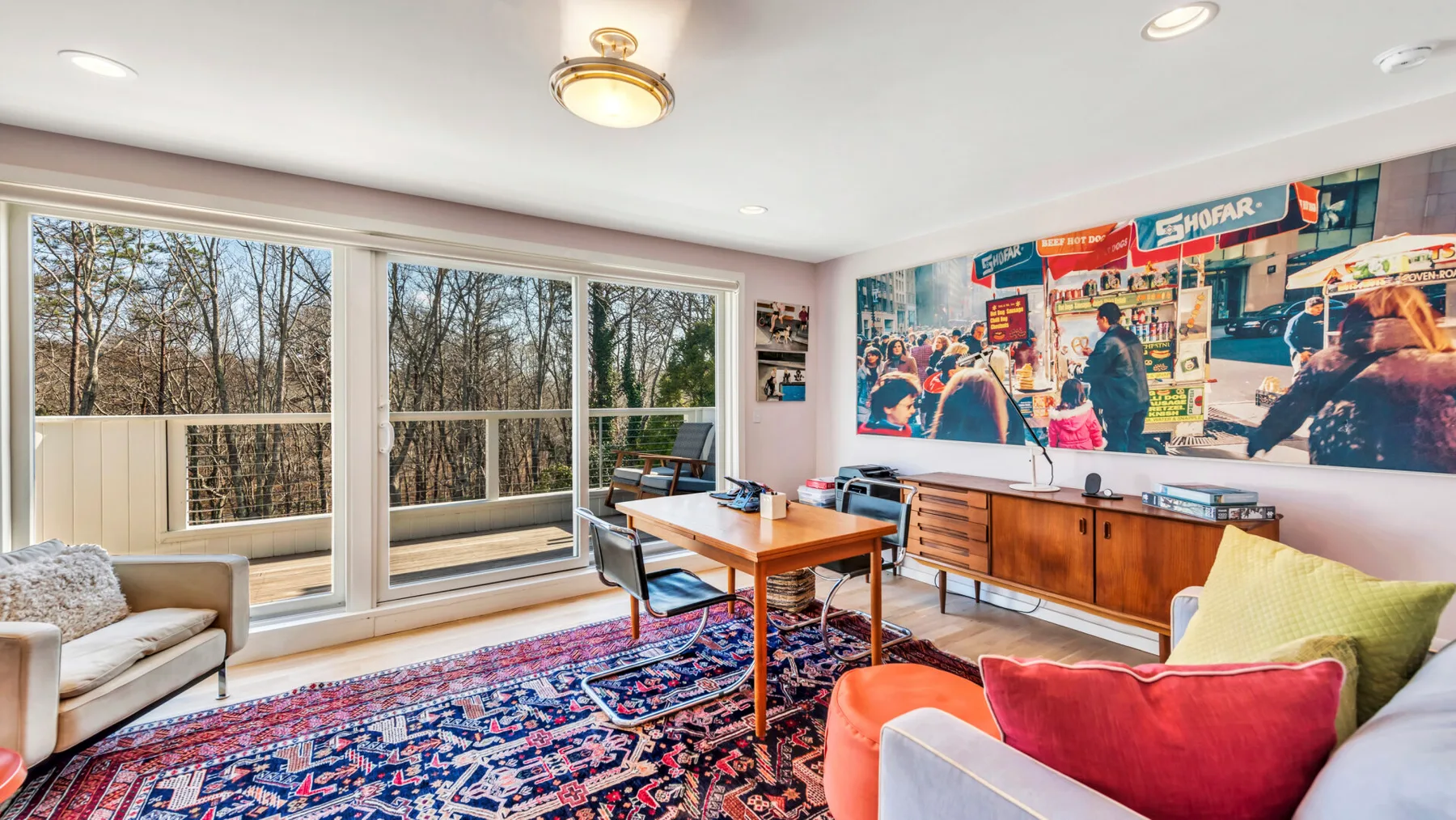 A bright living room with large windows, seating, and a patterned rug.