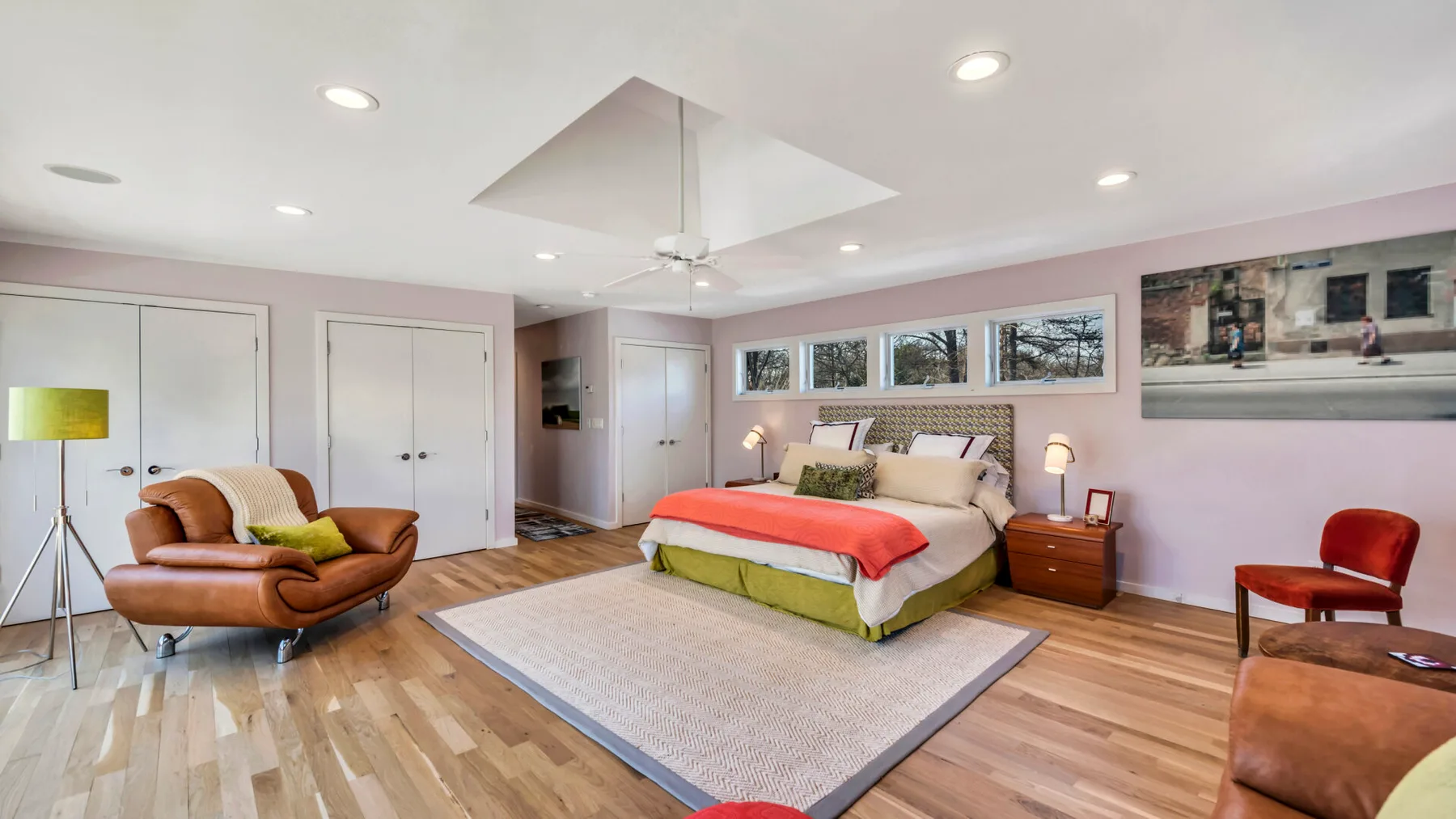 A bedroom with a large bed, bedside tables, and a rug on the wood floor.