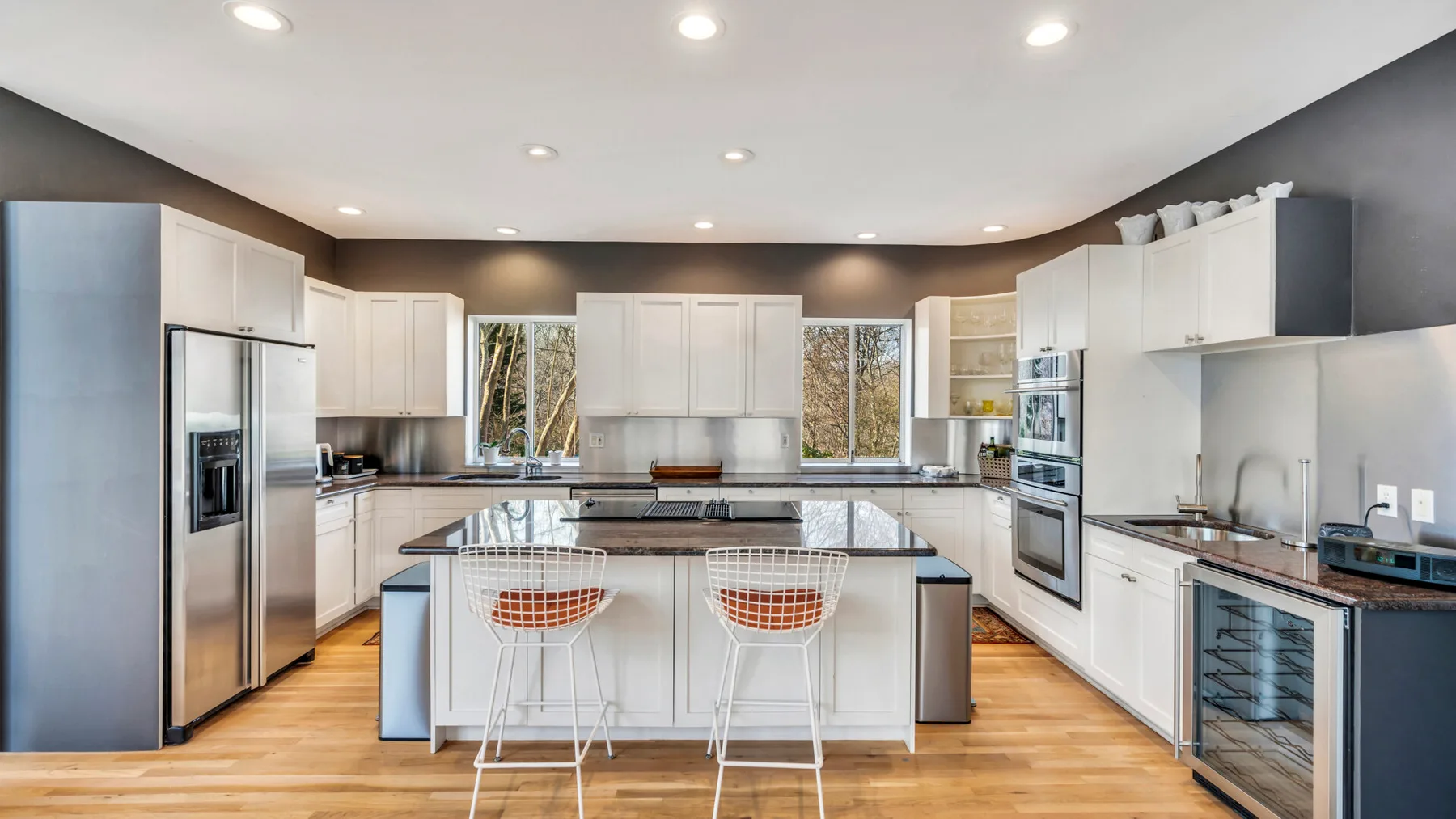 A bright kitchen with white cabinetry and a central island with seating.