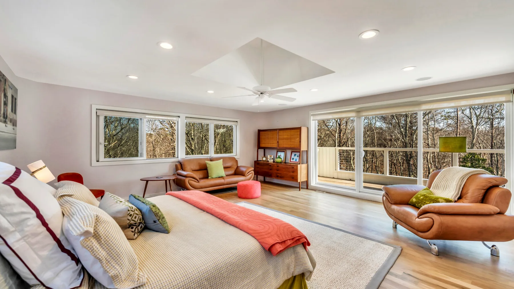 A bright living room with seating, large windows, and a television.