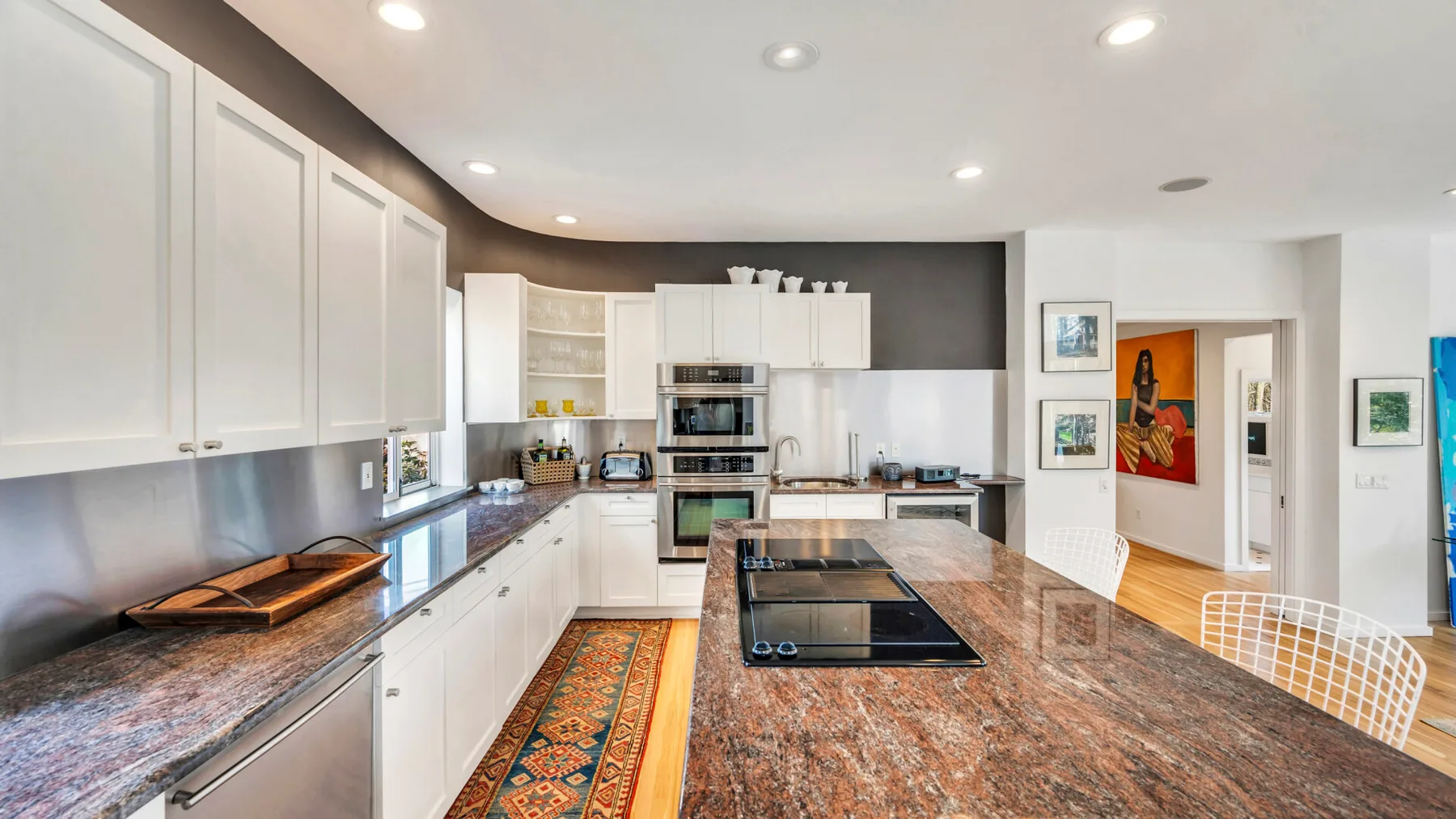 A modern kitchen with white cabinets and a large island with a cooktop.