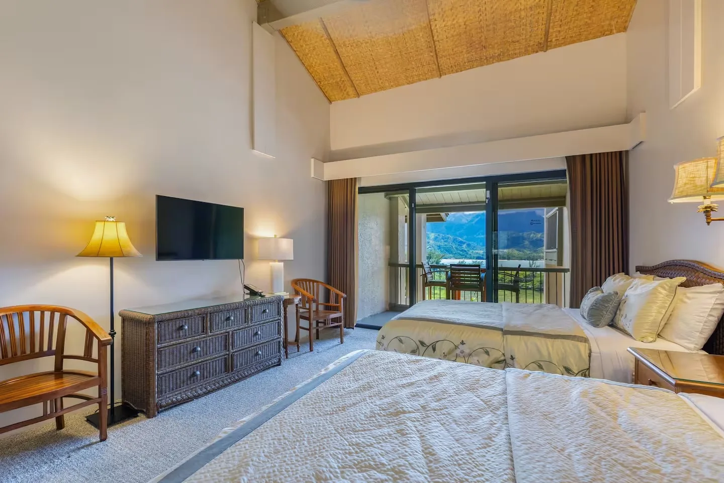 Un dormitorio luminoso con camas, asientos y puertas de vidrio que dan a un balcón.