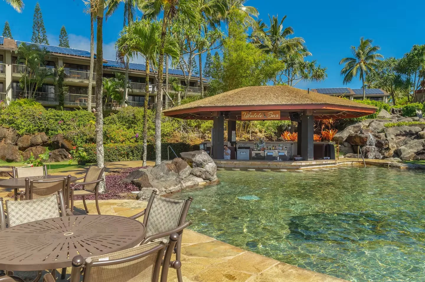 Una piscina tropical junto a un pabellón sombreado y asientos al aire libre.