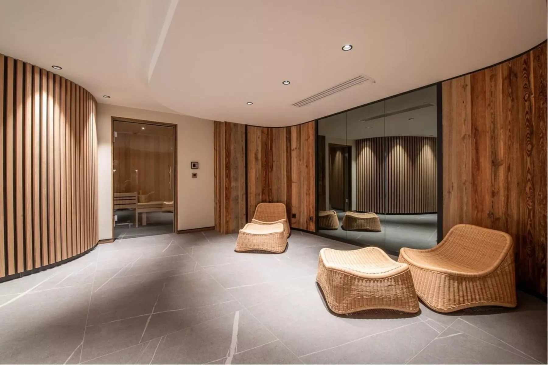 Una sala moderna con asientos tejidos, paredes revestidas de madera y un espejo grande.
