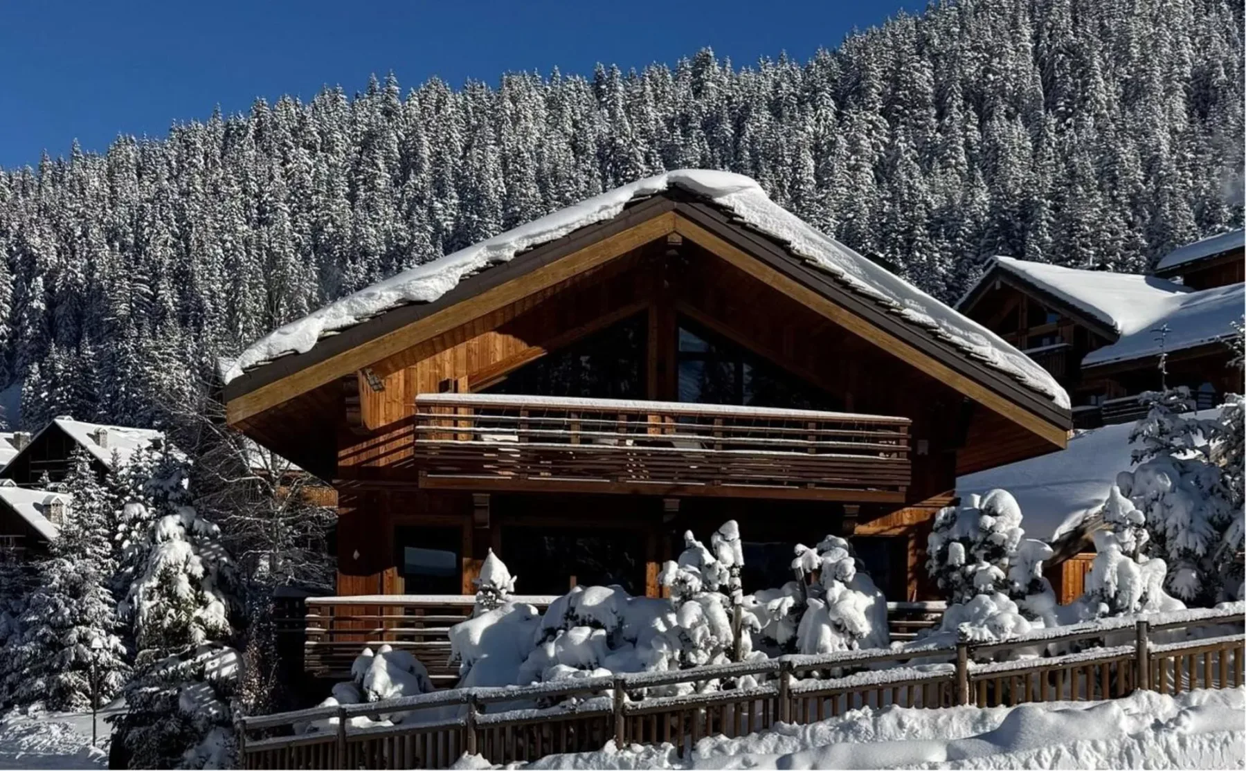 Un chalet de madera se encuentra bajo árboles cubiertos de nieve en la montaña.