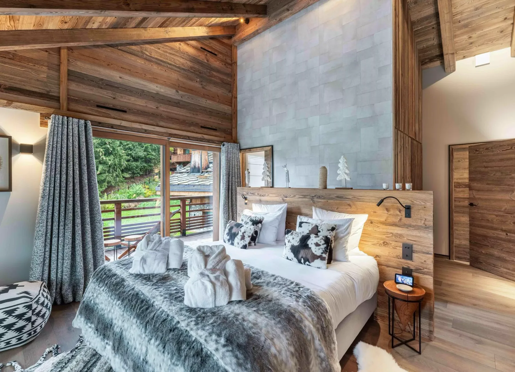 Un dormitorio con una cama junto a una puerta de vidrio y un techo alto.