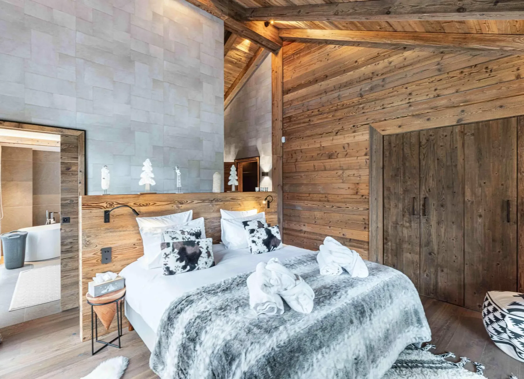 Dormitorio con una cama, paredes revestidas de madera y una puerta abierta al baño.