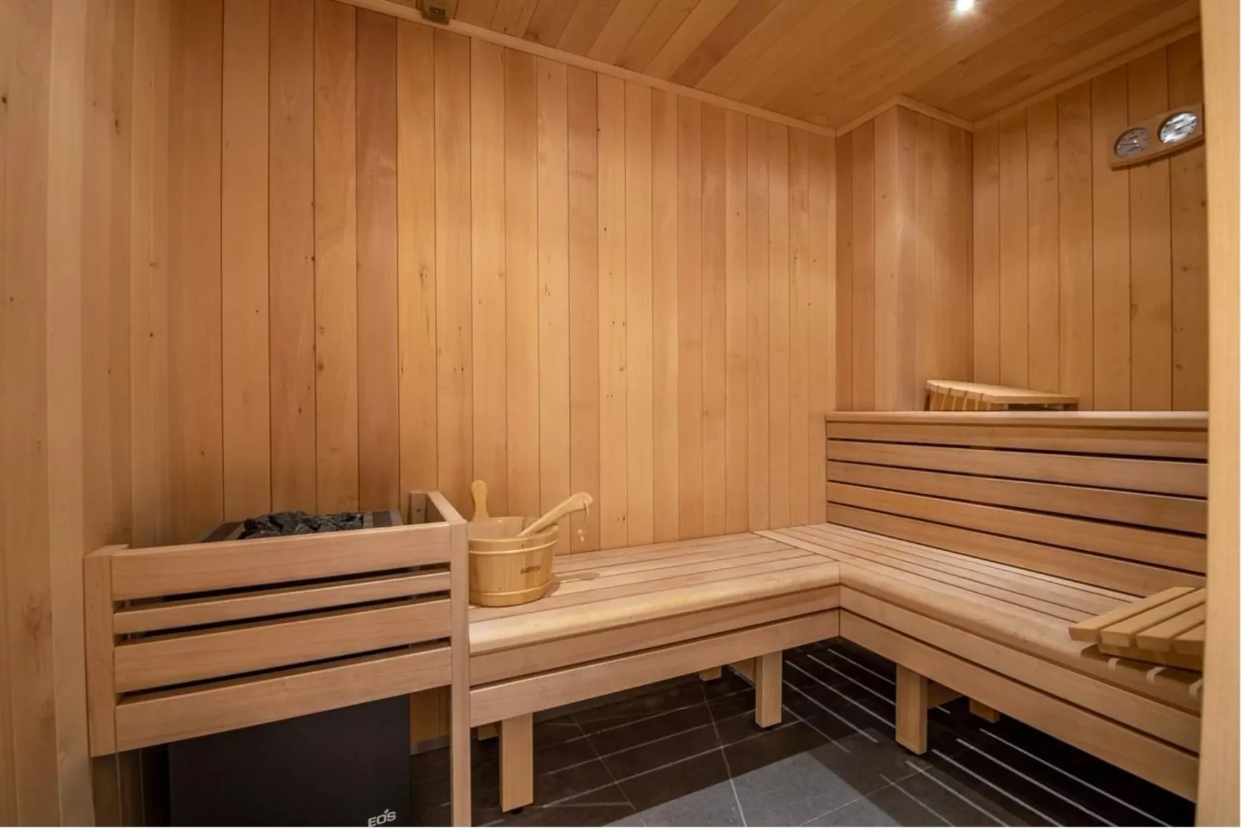 Una sauna revestida de madera con asientos escalonados y un cubo.