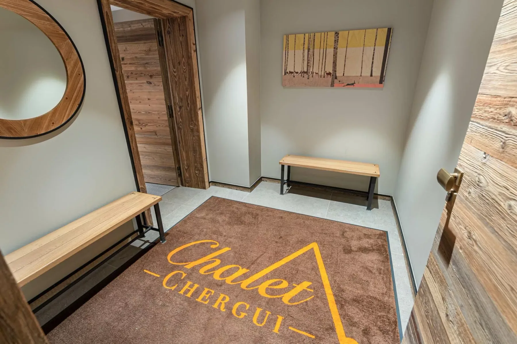 Una entrada con puertas de madera, bancos y una alfombra marrón.