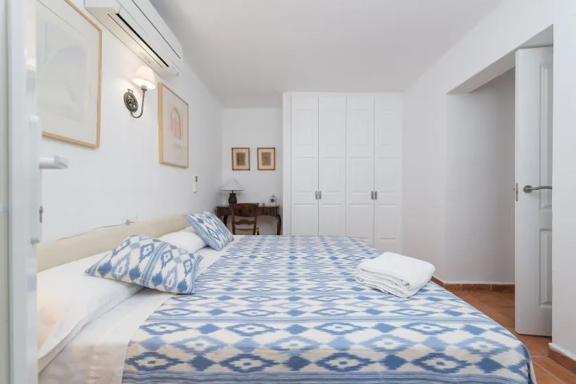 Un dormitorio con ropa de cama estampada azul y blanca y armarios blancos.