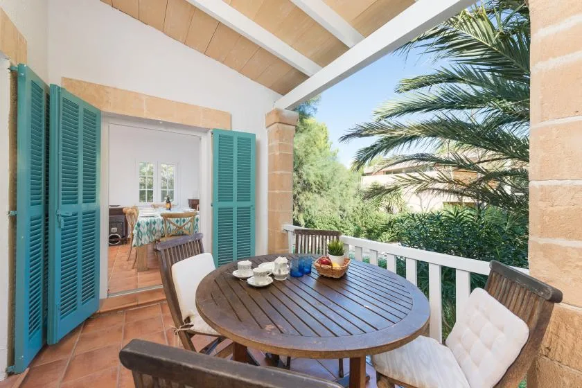 Un patio cubierto con una mesa redonda da a la vegetación y las hojas de una palmera.