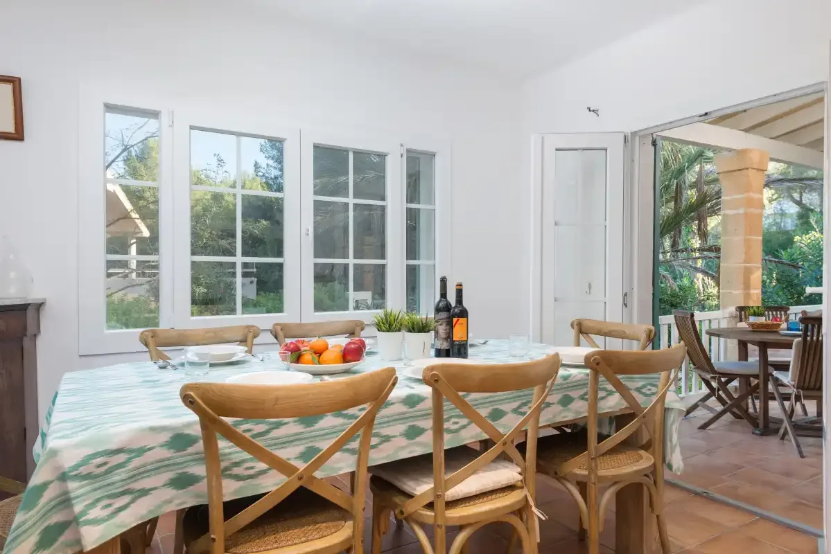Un comedor con una mesa larga junto a grandes ventanas.
