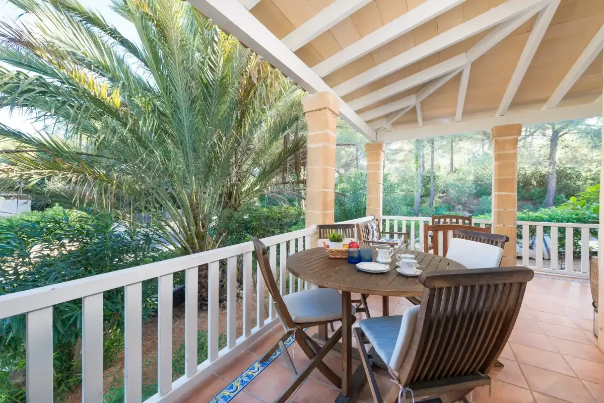 Una zona de comedor exterior cubierta con una mesa y asientos junto a un jardín.