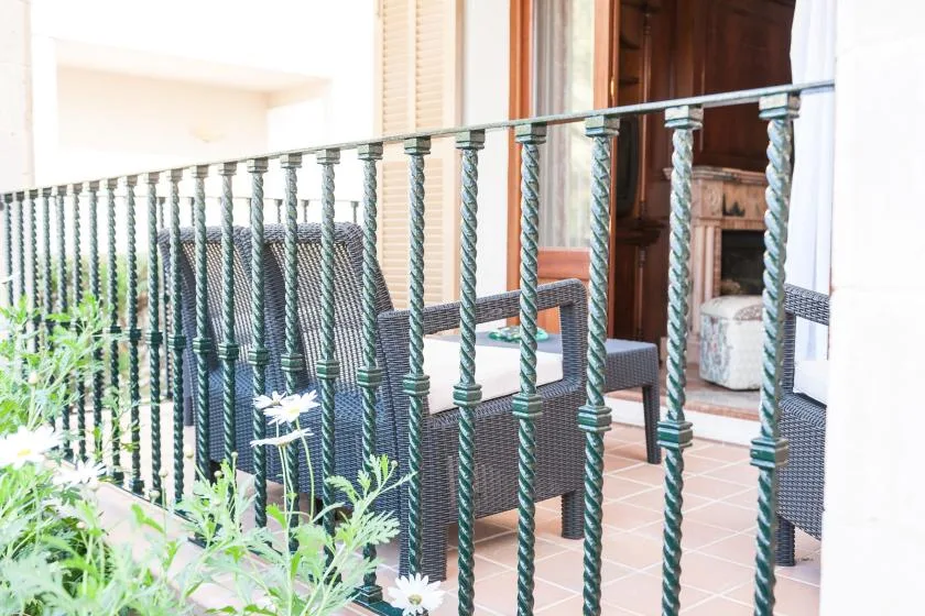 A tiled balcony with dark seating and a metal railing overlooks leafy plants.