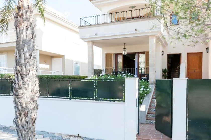 A white house entrance with a gated front patio and outdoor steps.