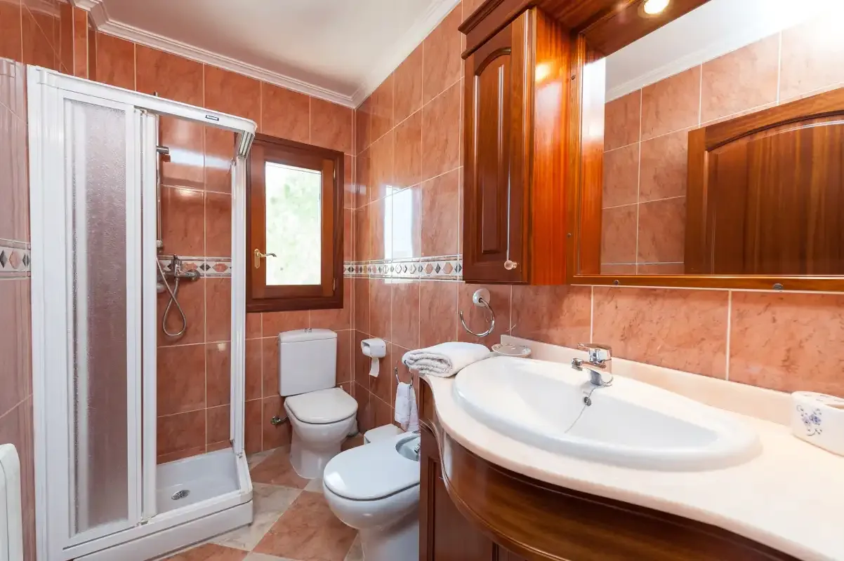 A tiled bathroom with a shower, toilet, and wide sink.