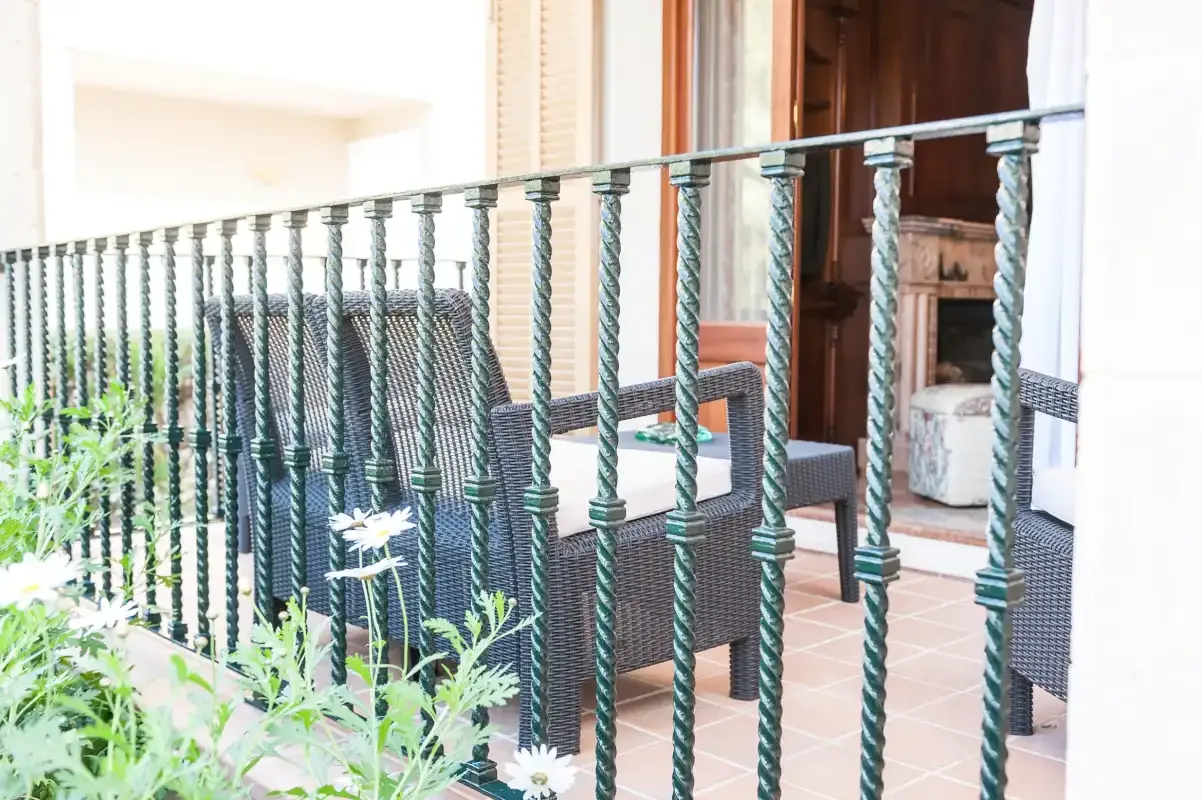 A tiled patio with dark woven seating behind a metal railing.