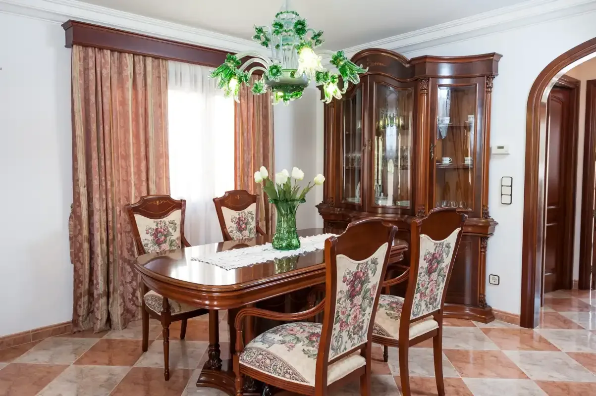 A formal dining room with a wooden table and floral-upholstered seating.