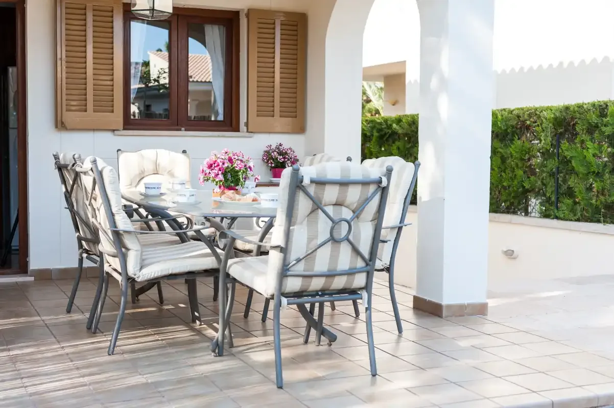 A tiled patio dining area with cushioned seating and flowers on the table.