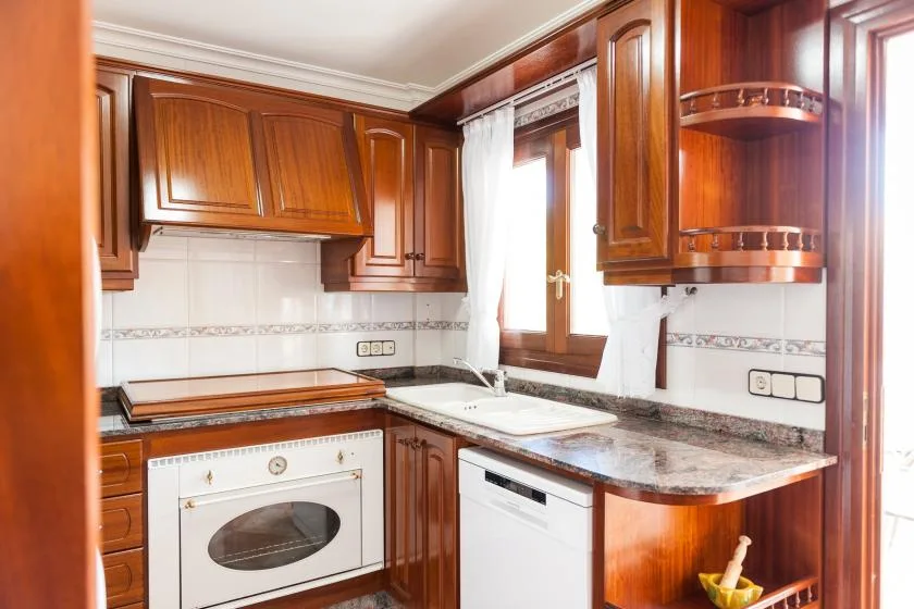 A kitchen with wooden cabinets, a countertop, and a built-in oven.