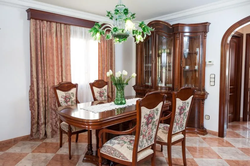 A formal dining room with a wooden table, upholstered seating, and a glass-front cabinet.