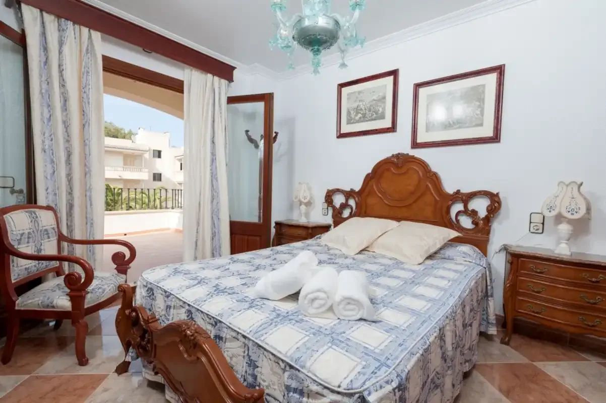 A bedroom with a bed dressed in blue-and-white bedding and wooden furniture.