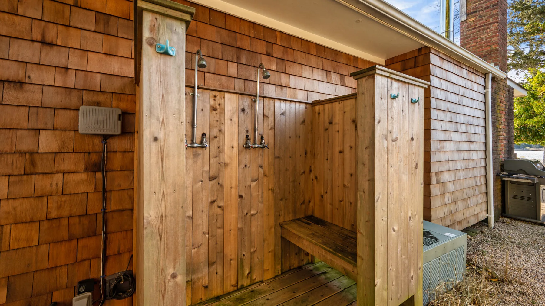 Una zona de ducha exterior con paneles de madera y un banco.