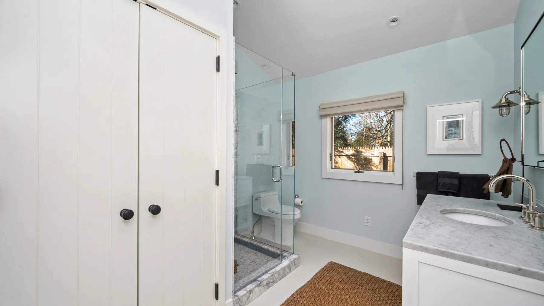 Un baño luminoso con ducha de vidrio, lavabo y ventana.
