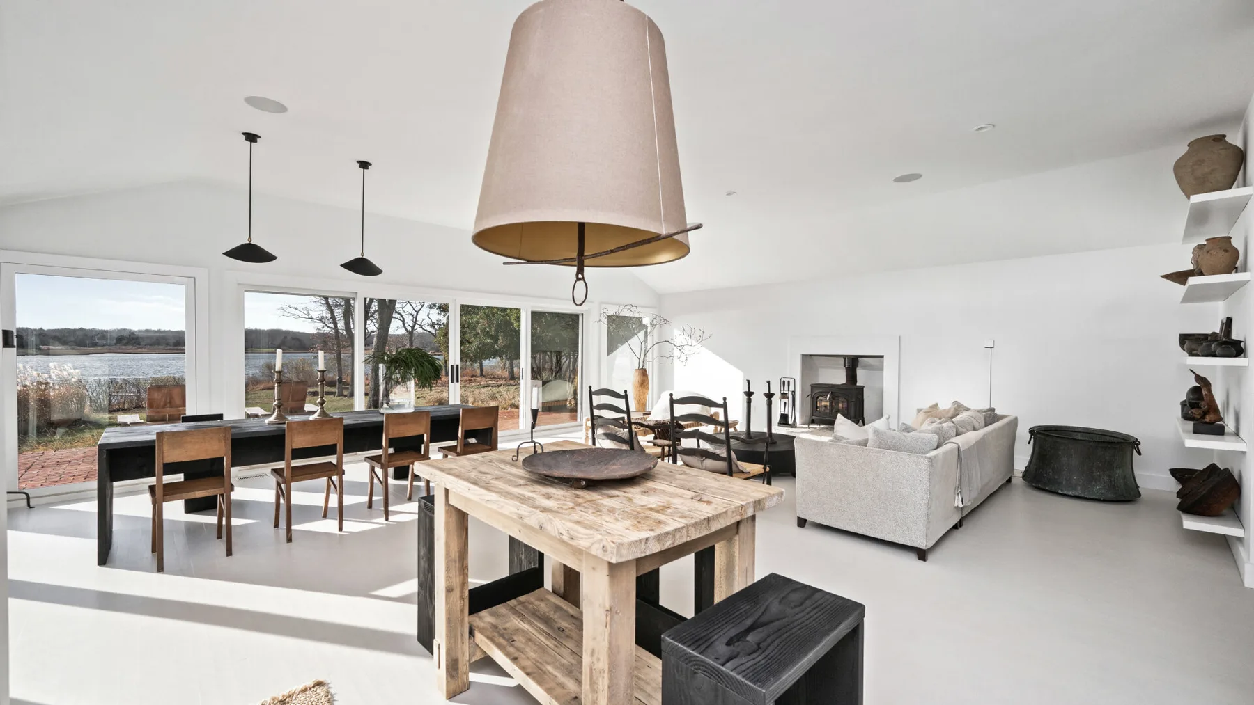 Una luminosa sala diáfana con comedor, grandes ventanales y una mesa de madera.