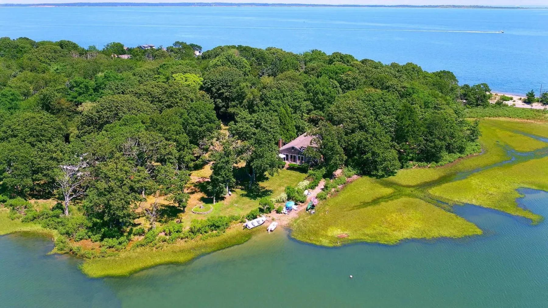 Vista aérea de una orilla arbolada con una casa junto al agua.