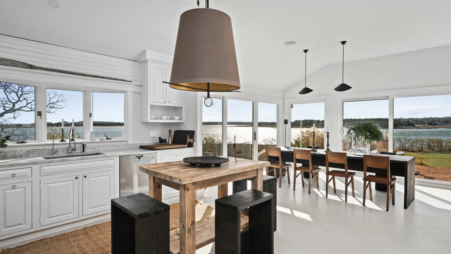Una luminosa cocina abierta al comedor, con una isla de madera y una mesa larga.