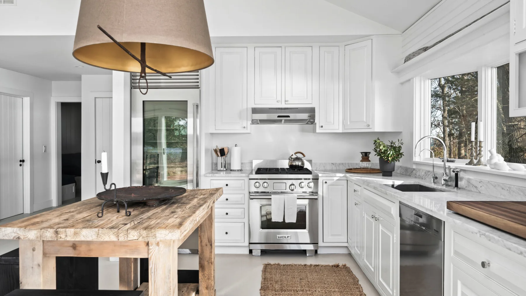 Una cocina luminosa con gabinetes blancos, electrodomésticos de acero inoxidable e isla de madera.