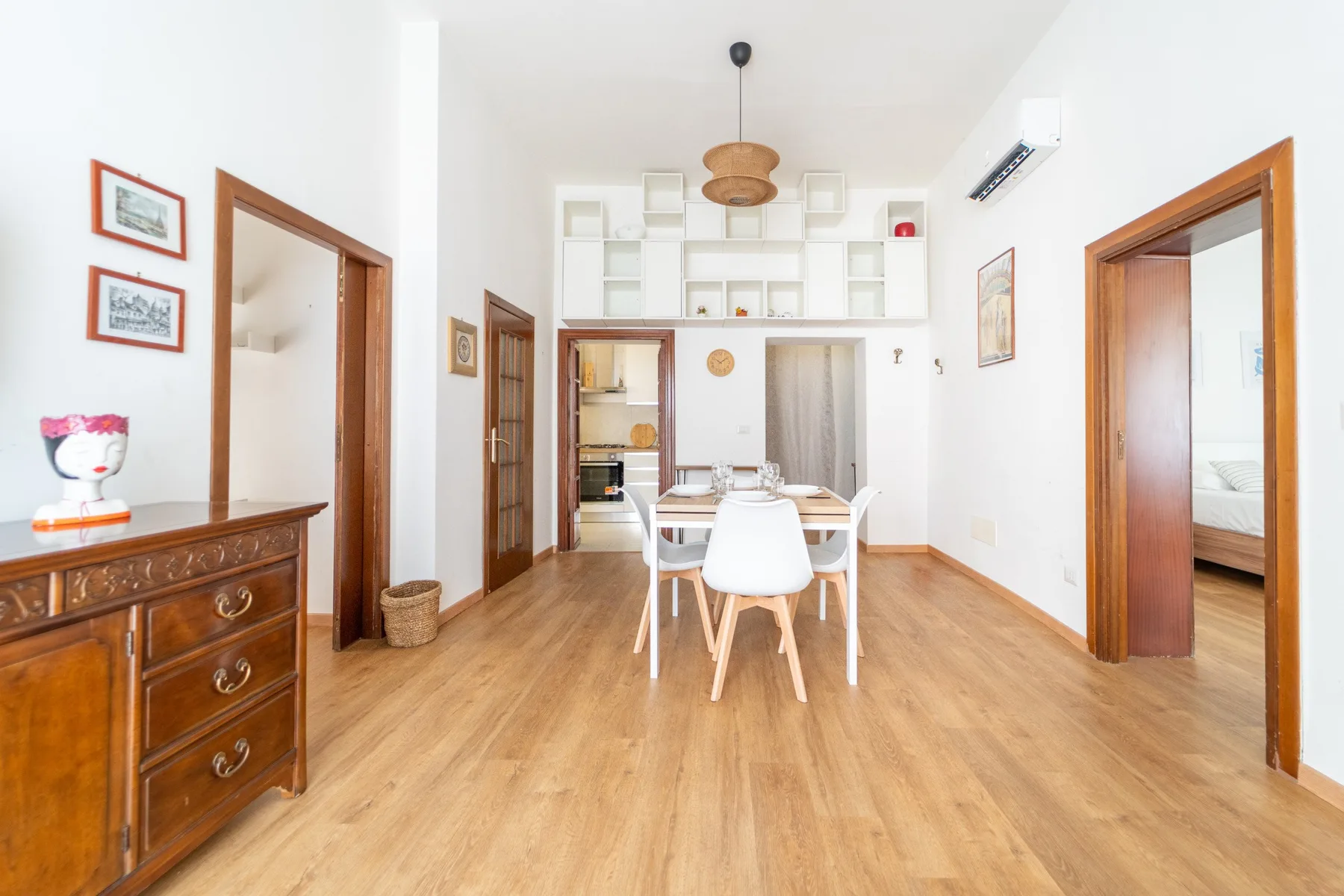 A bright dining area with a wooden table and chairs beneath a hanging light.