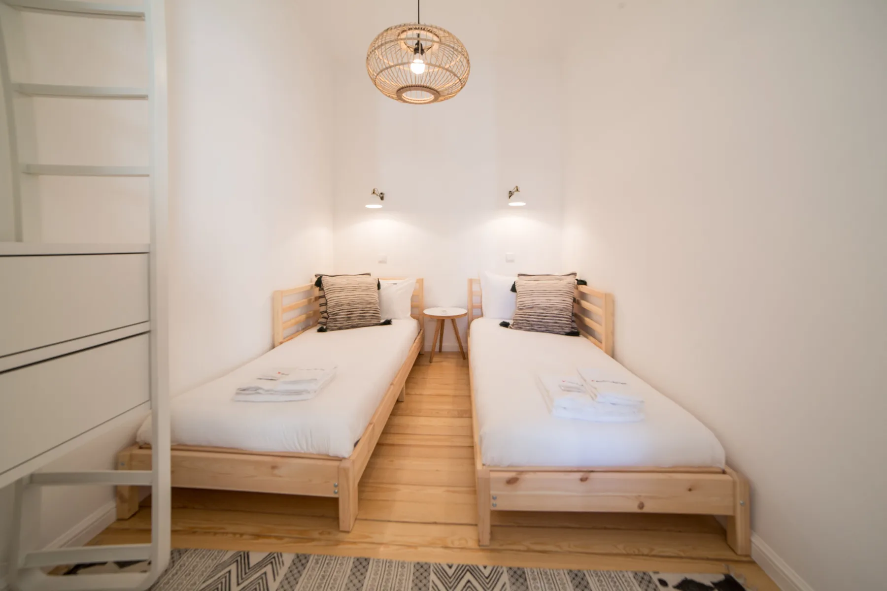 A bright bedroom with two single beds and a small table between them.