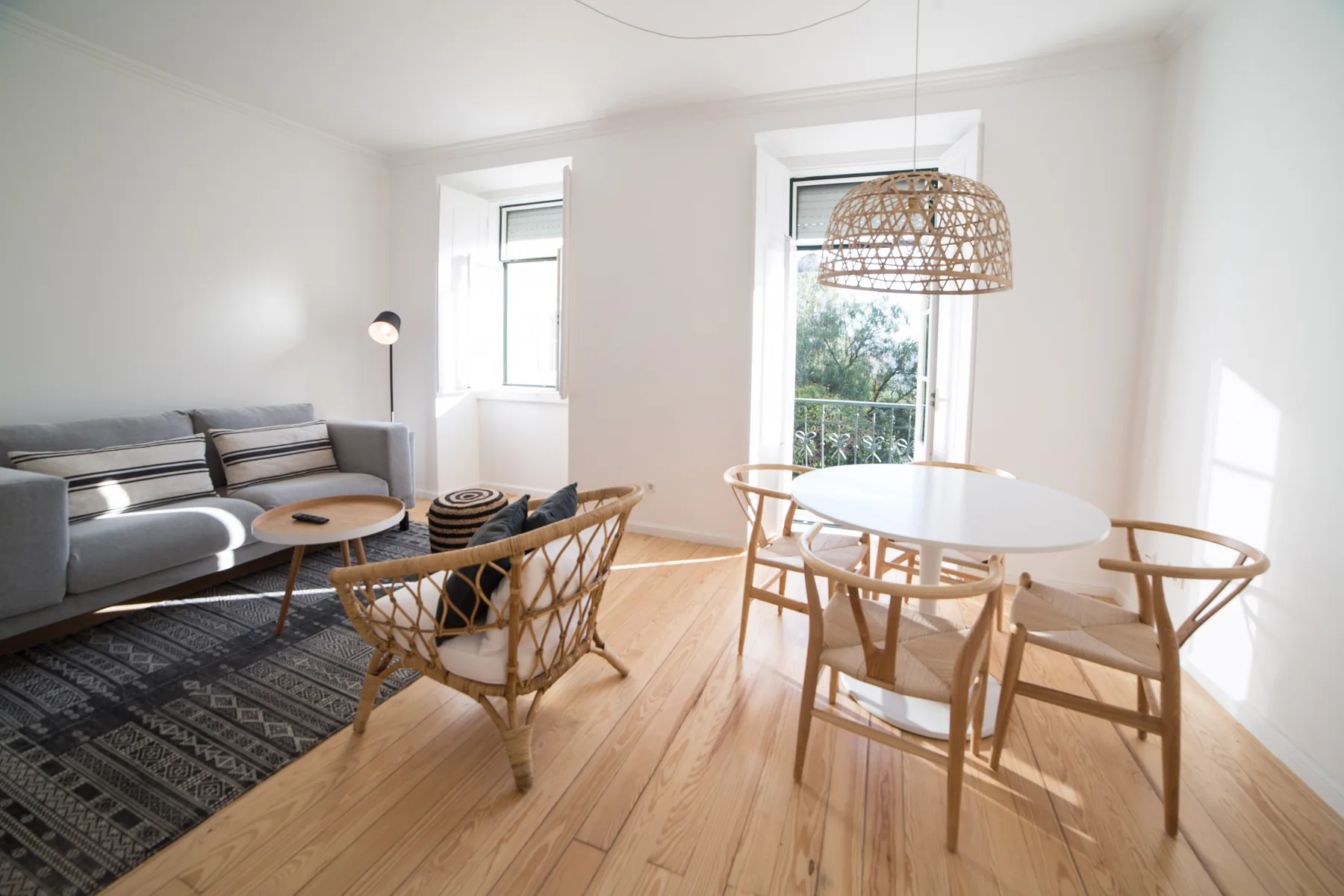 A bright living and dining area with seating, a table, and large windows.