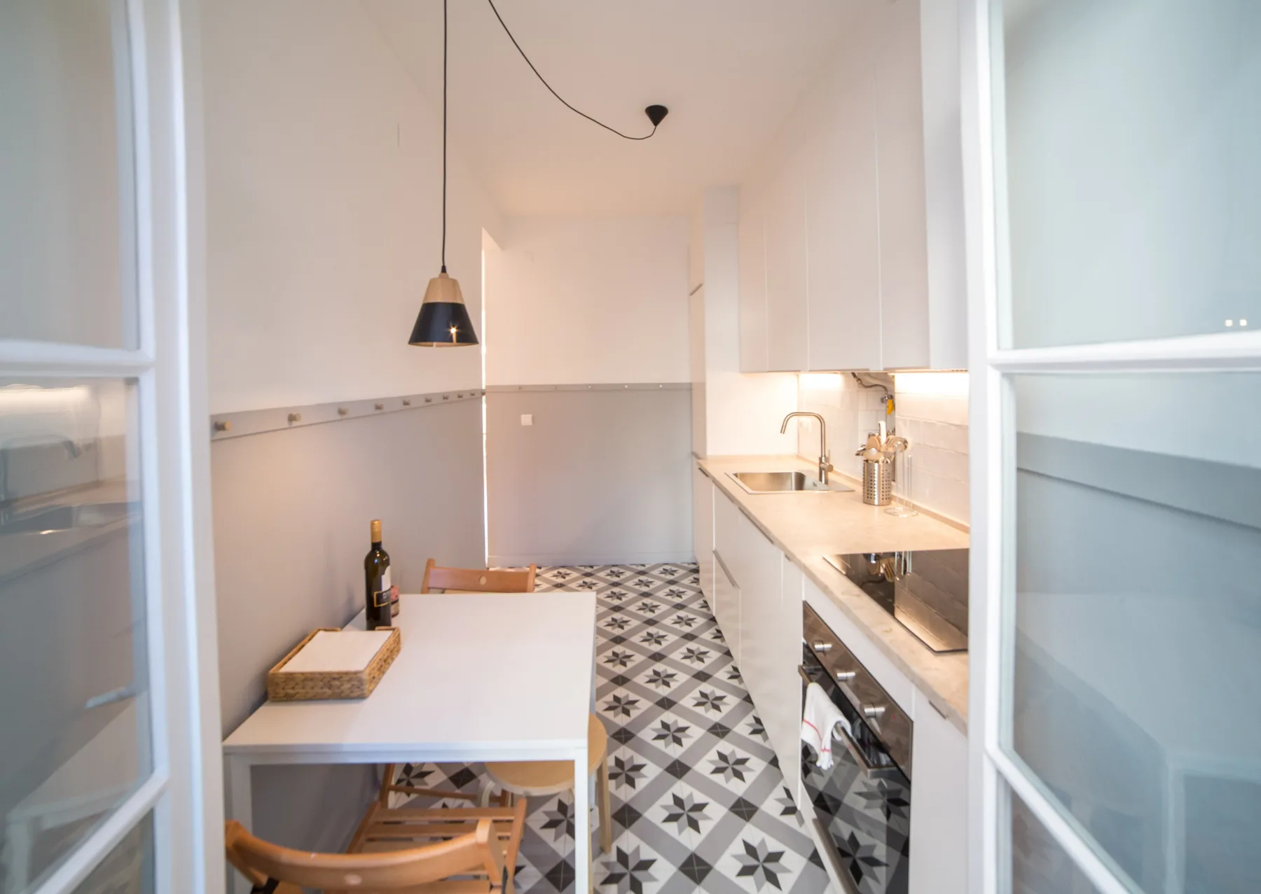 A bright kitchen with a dining table and patterned floor tiles.