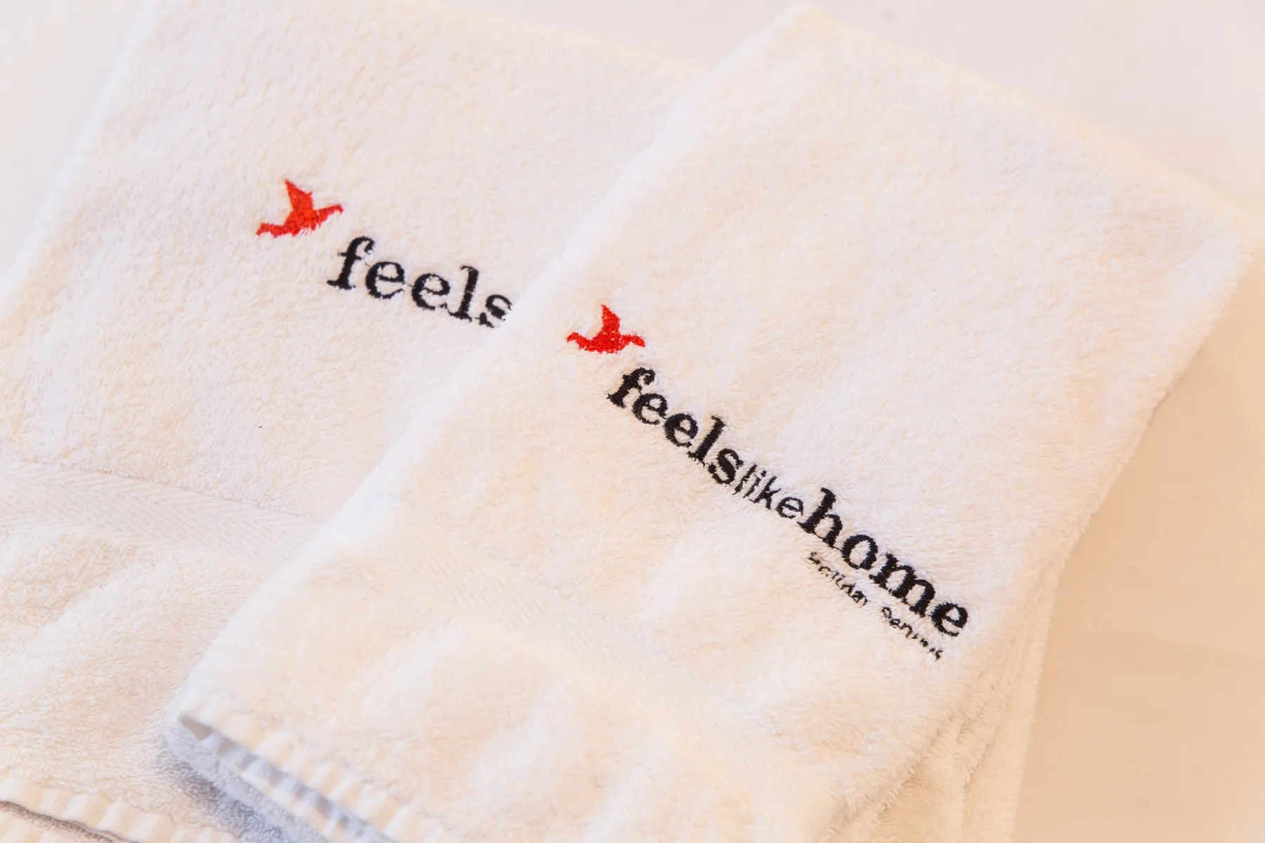 White towels with red bird logos and black lettering are laid out together.