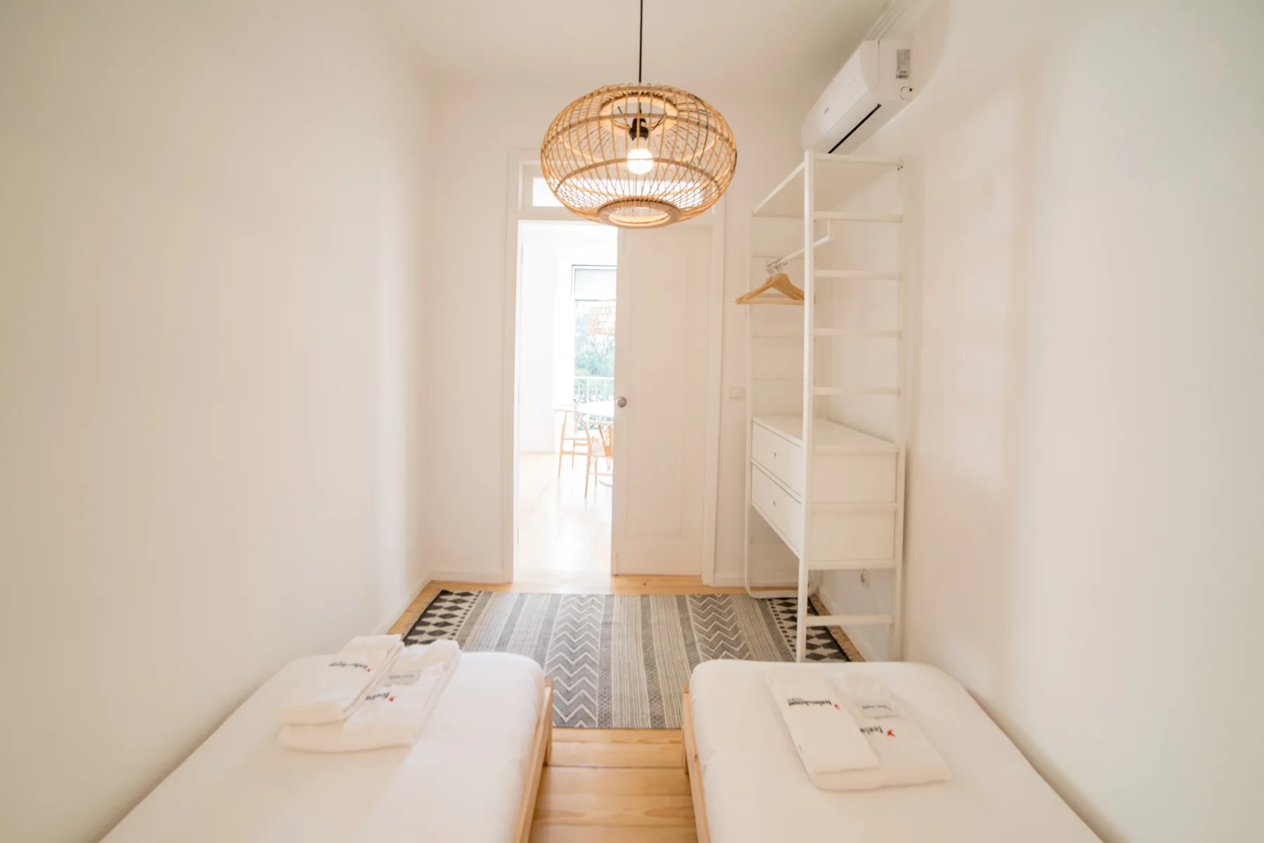 A bright bedroom with two beds and open shelving.