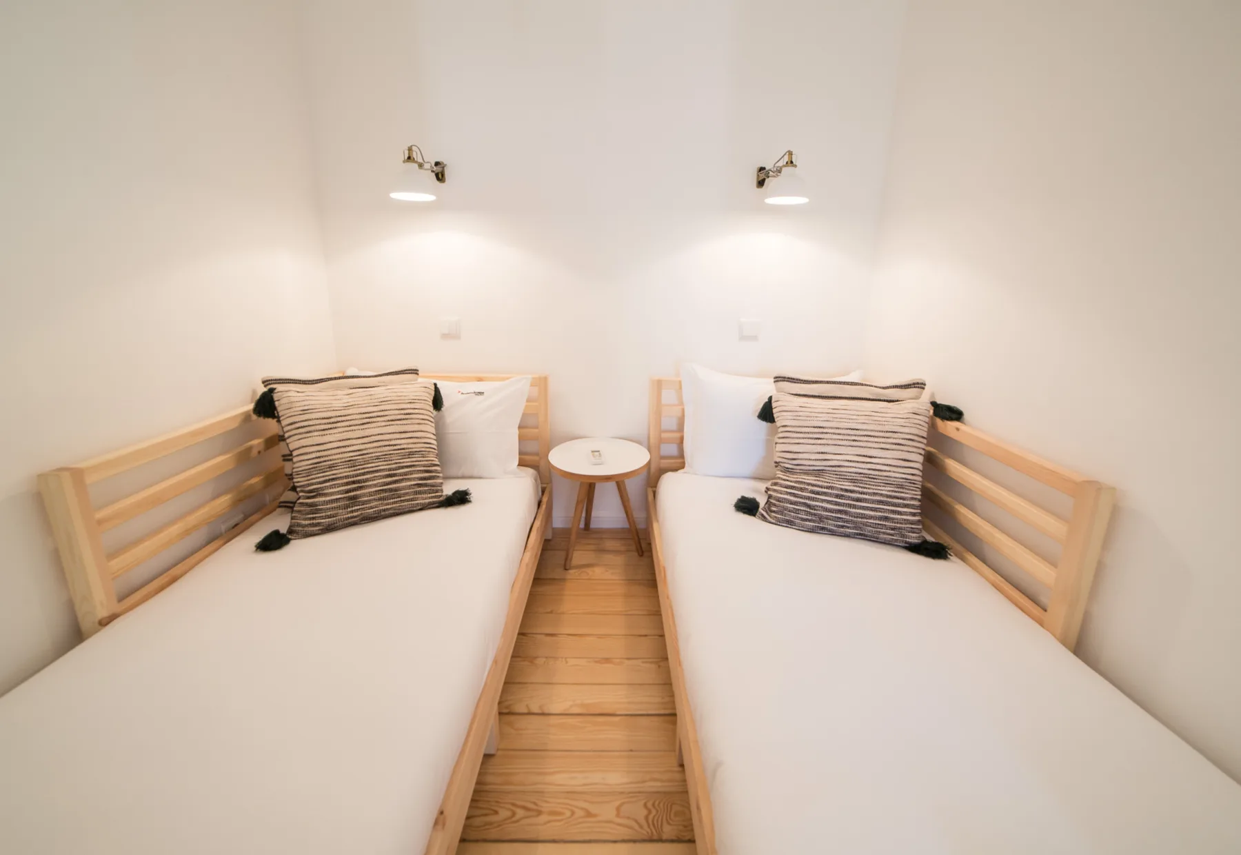 A bright bedroom with two single beds and a small table between them.