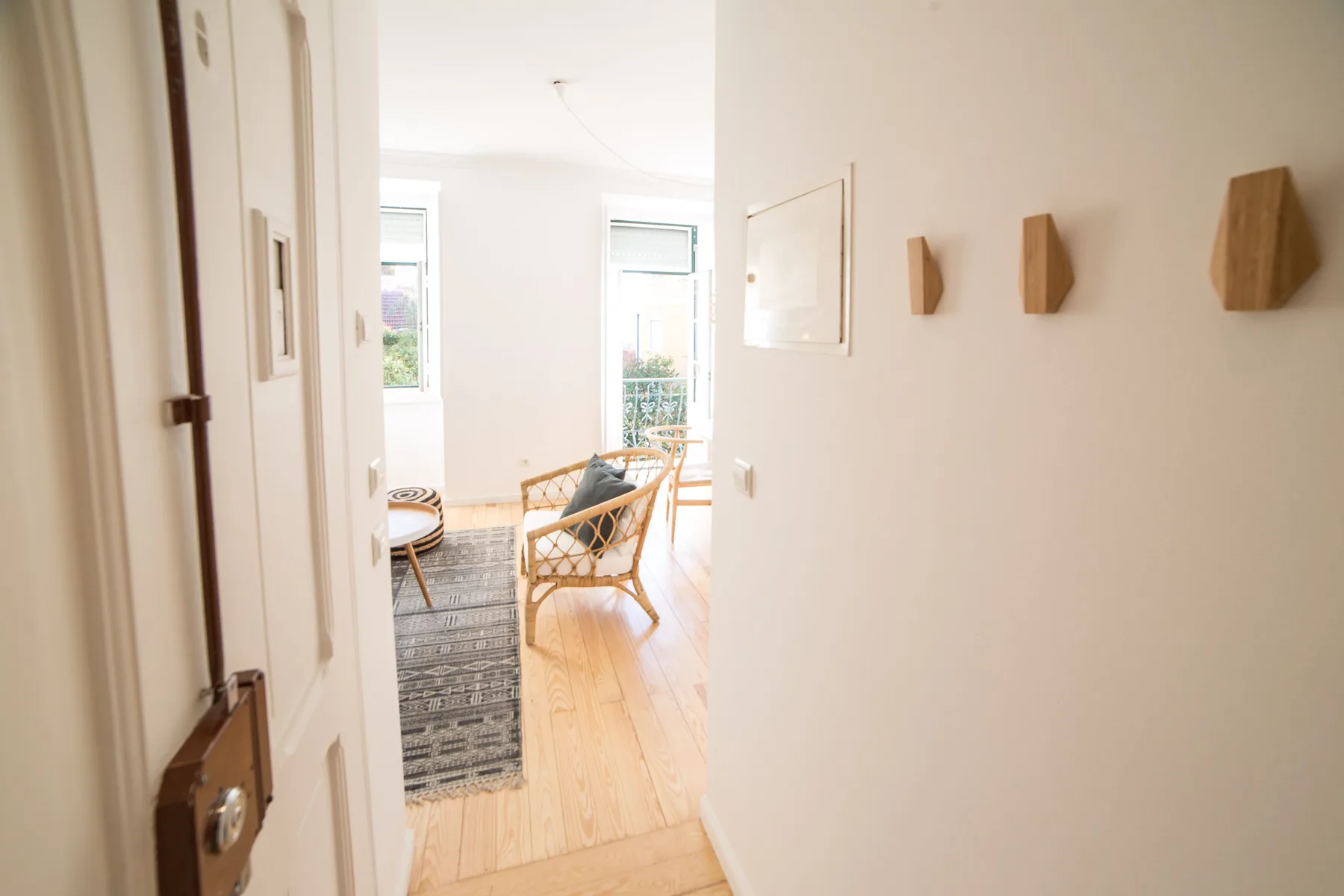 A bright living room with seating beside tall windows and a patterned rug.