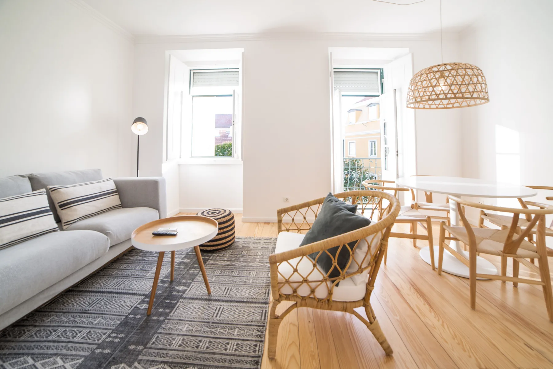 A bright living and dining area with seating, a table, and large windows.