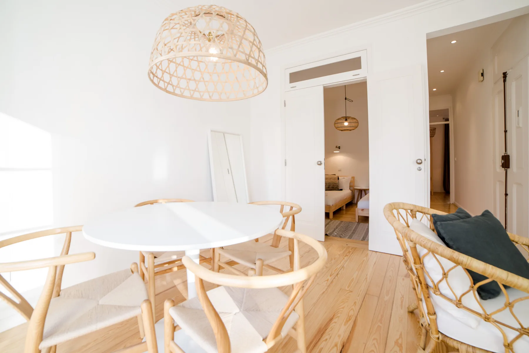 A bright dining area with a round table and woven pendant light.
