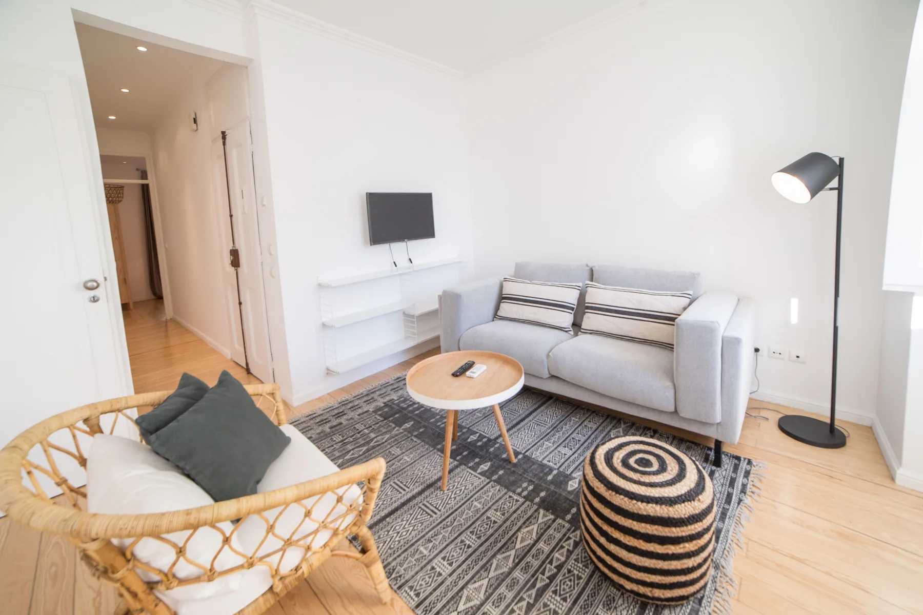 A bright living room with seating around a patterned rug and coffee table.