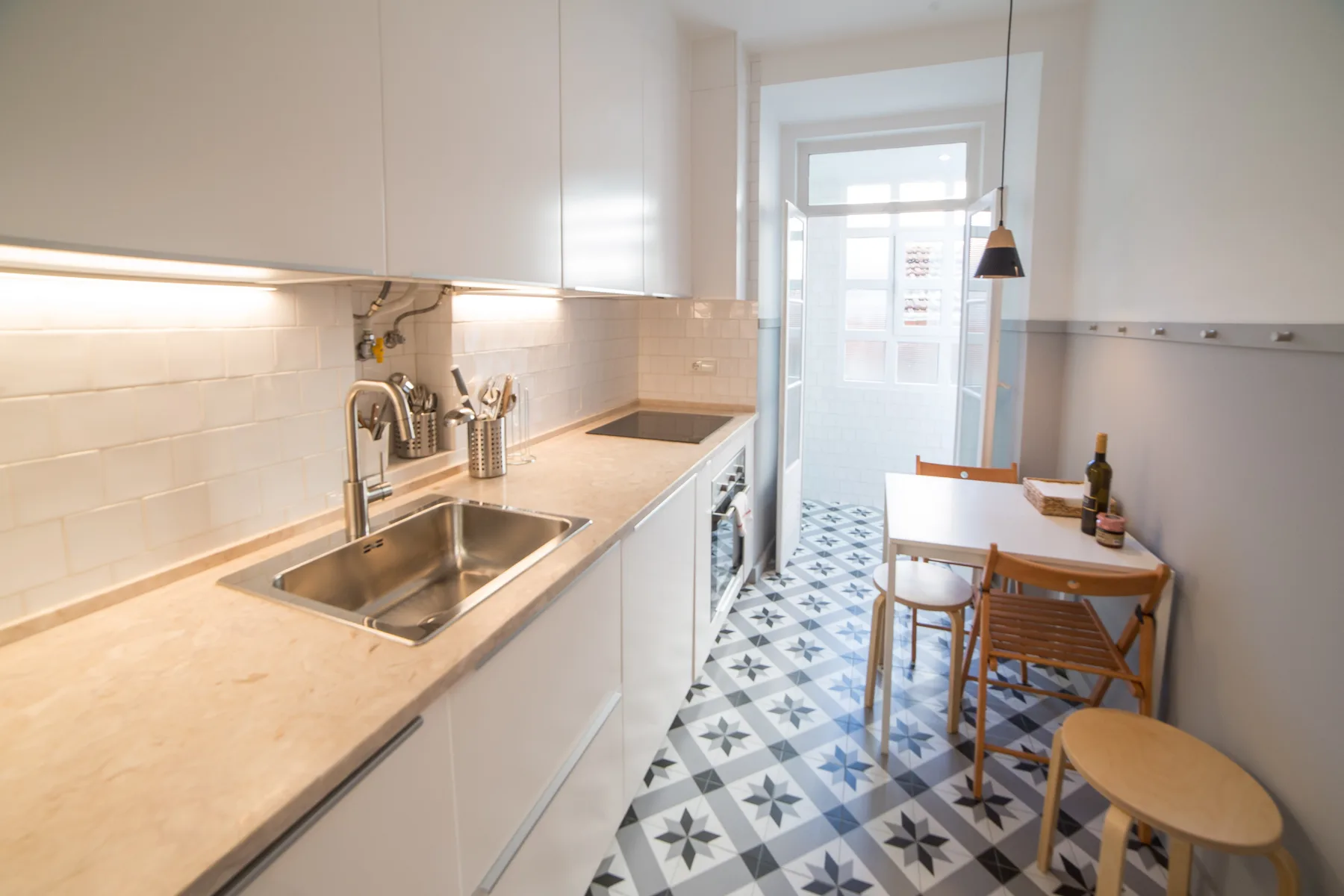 A bright kitchen with a dining table beside a patterned tile floor.