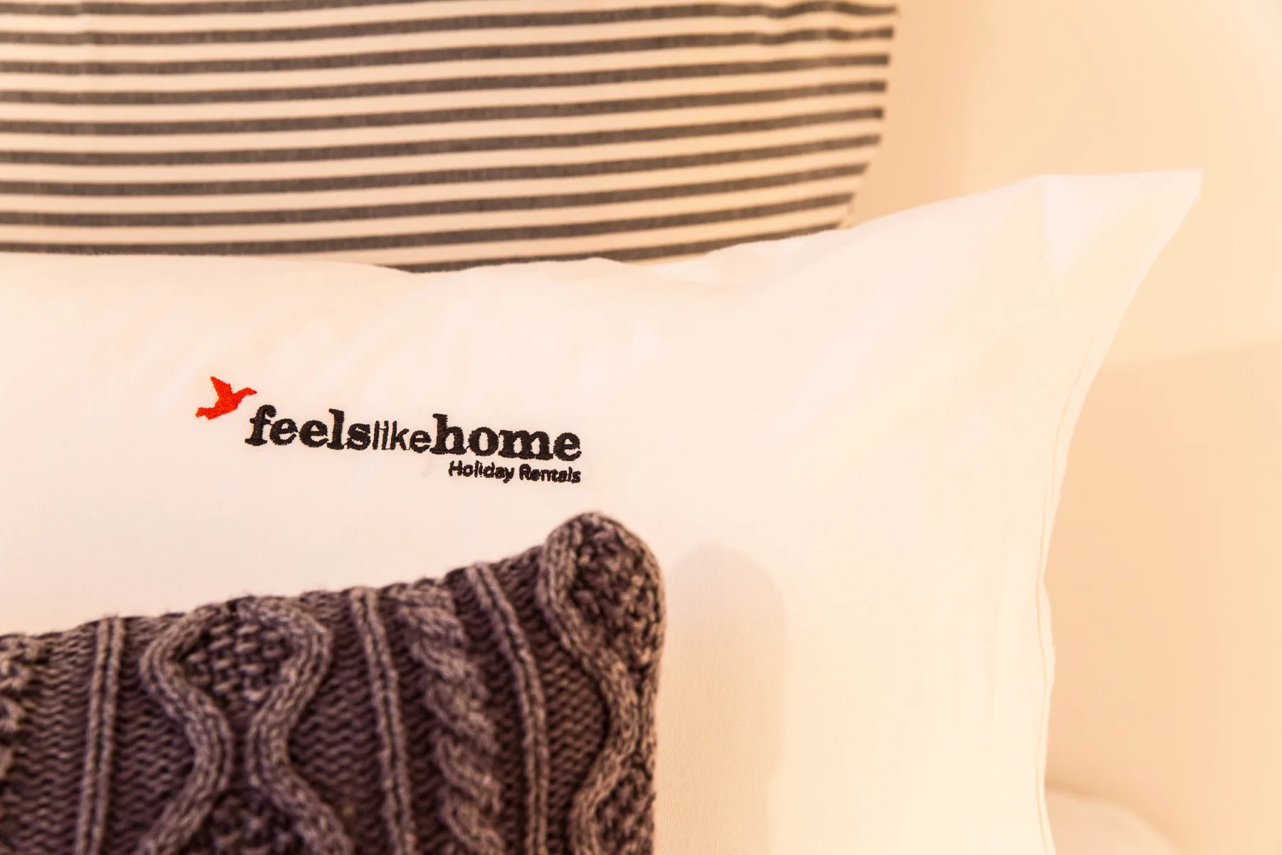 Bedroom close-up of a white pillow with a dark knitted cushion.