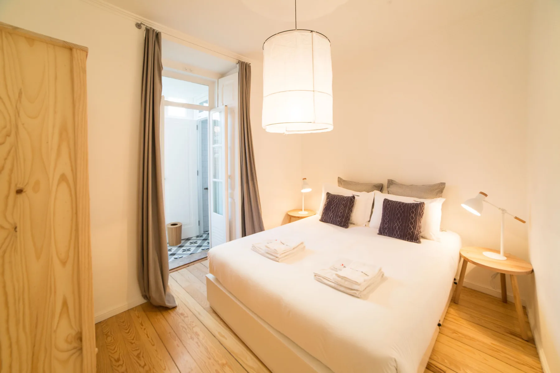 A bright bedroom with a double bed and a doorway to an adjoining space.